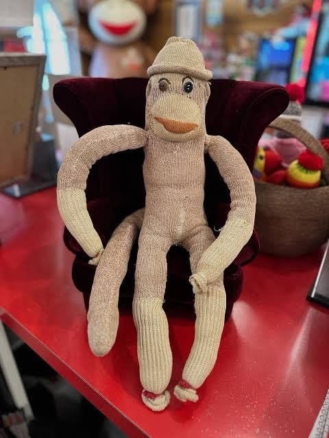 Luno, the real handmade 1930s sock monkey, sitting in a tiny velvet armchair